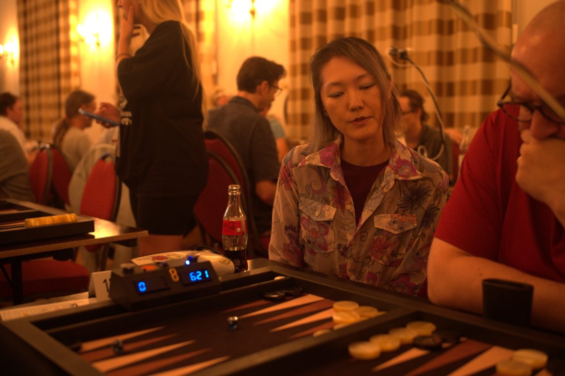 Backgammon Doppel WM in Aachen Eine Frau betrachtet ein Backgammon-Spiel in einem geschäftigen Raum